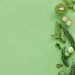 Colorful arrangement of fresh green fruits and vegetables on a green background, top view, with copy space.
